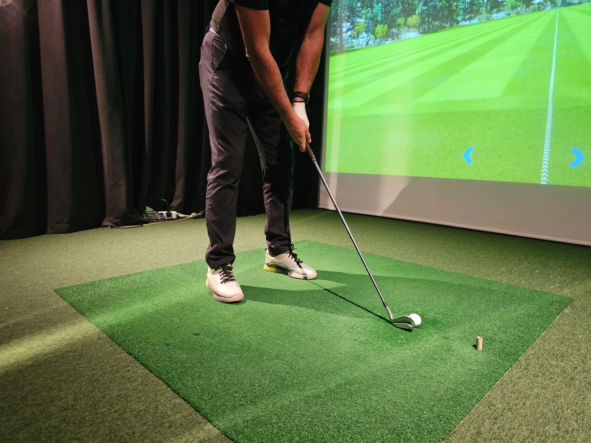 Golfer swinging indoors in golf simulator