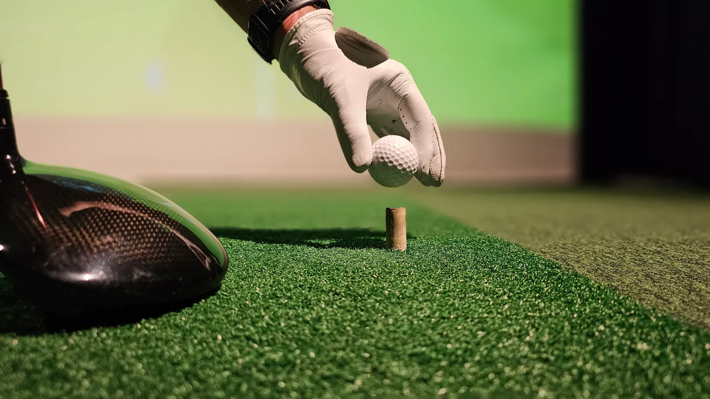 Golf ball being placed on a tee inside a golf simulator